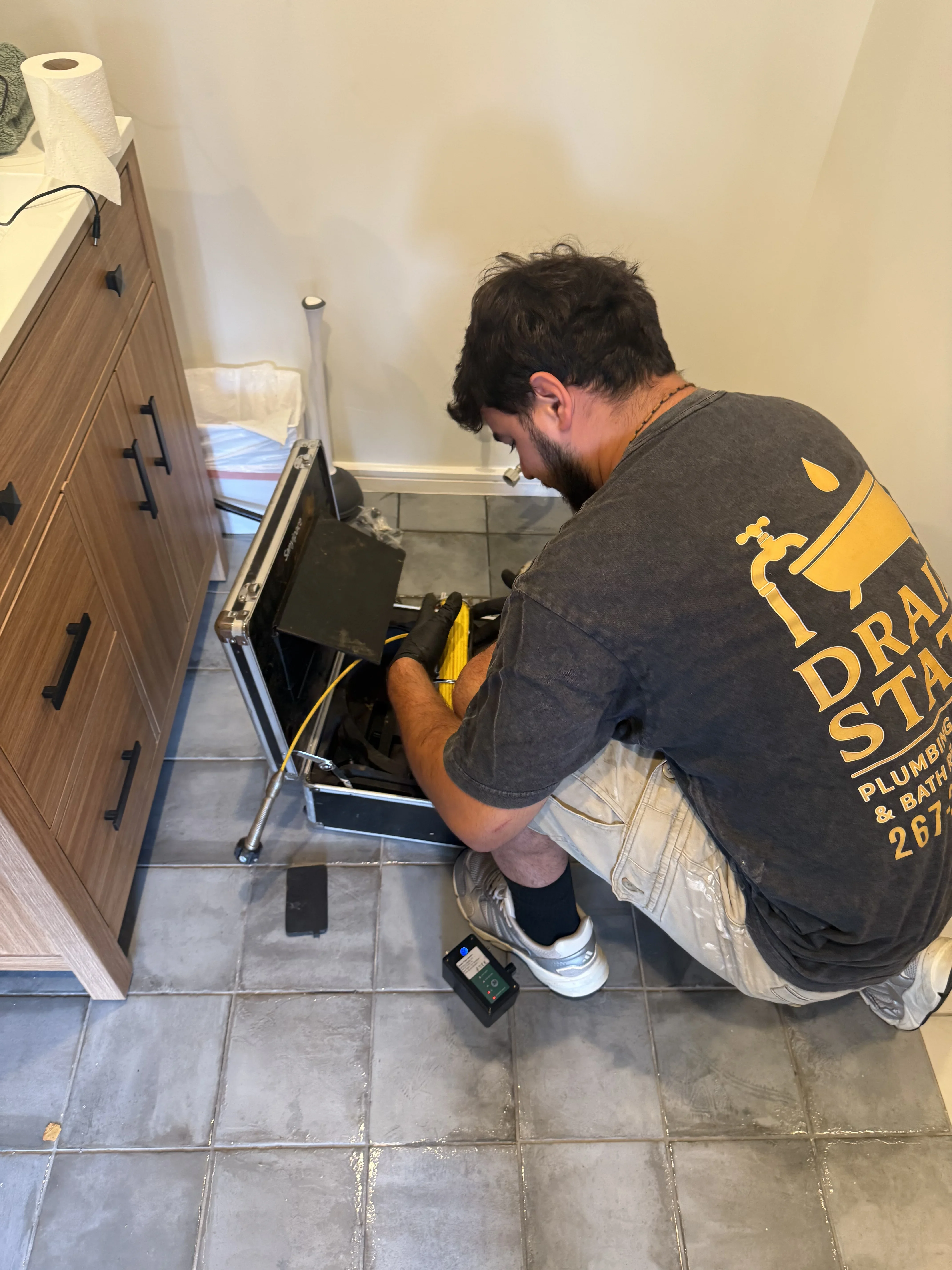 Plumber inspecting kitchen sink drain assembly and P-trap connections under sink