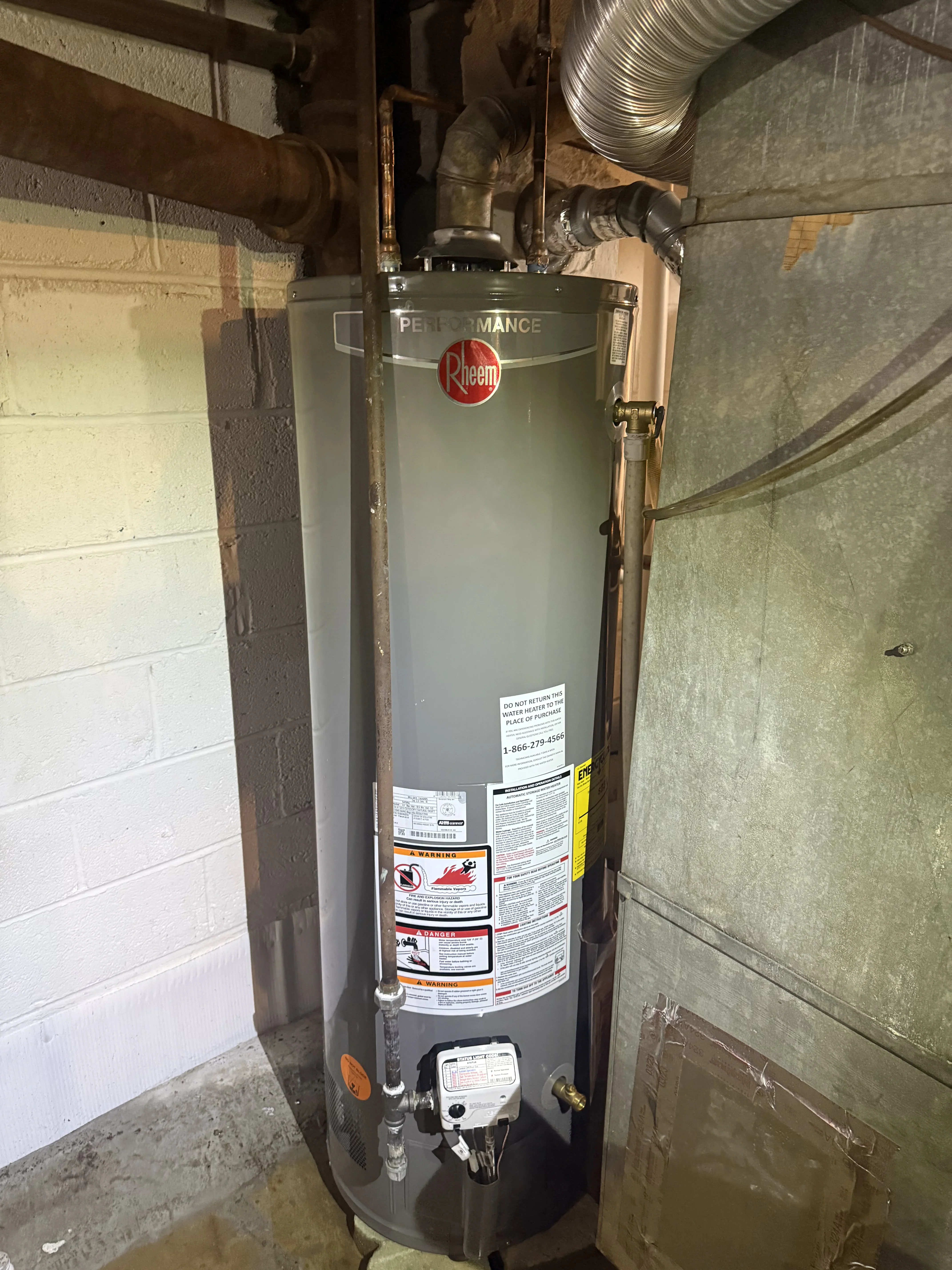 Rheem Performance gas water heater with metal vent ducting and brass connections installed in basement