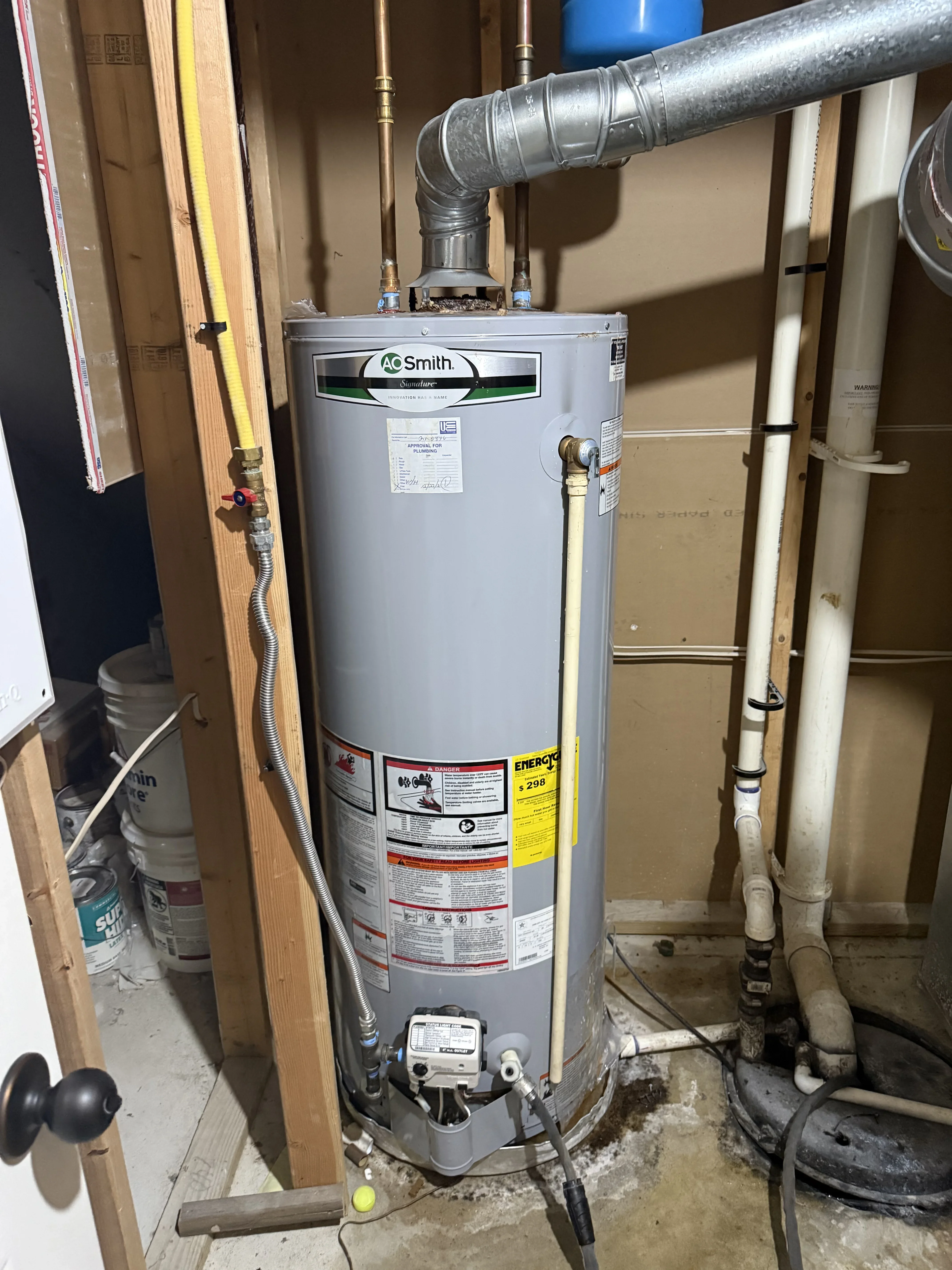 A.O. Smith gas water heater with galvanized vent pipe and copper supply connections in utility space